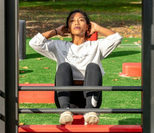 유산소 운동과 근력 운동의 균형 맞추기 woman in white long sleeve shirt and black pants sitting on red metal frame
