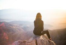 운동과 심리적 안정의 상관관계 person sitting on top of gray rock overlooking mountain during daytime
