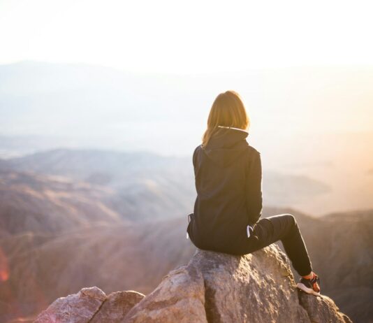 운동과 심리적 안정의 상관관계 person sitting on top of gray rock overlooking mountain during daytime