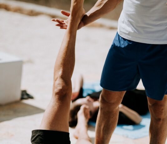 겨울철 숙면을 돕는 요가 자세 man lying on floor near man standing holding his leg