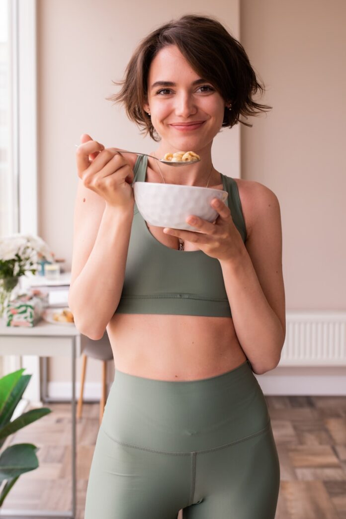 Photo by Look Studio a woman in a sports bra top holding a bowl of food