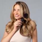 요즘 뜨는 ‘두피·헤어 루틴’, 건강한 머릿결을 위한 실천법은? a woman holding a hair brush in her hand