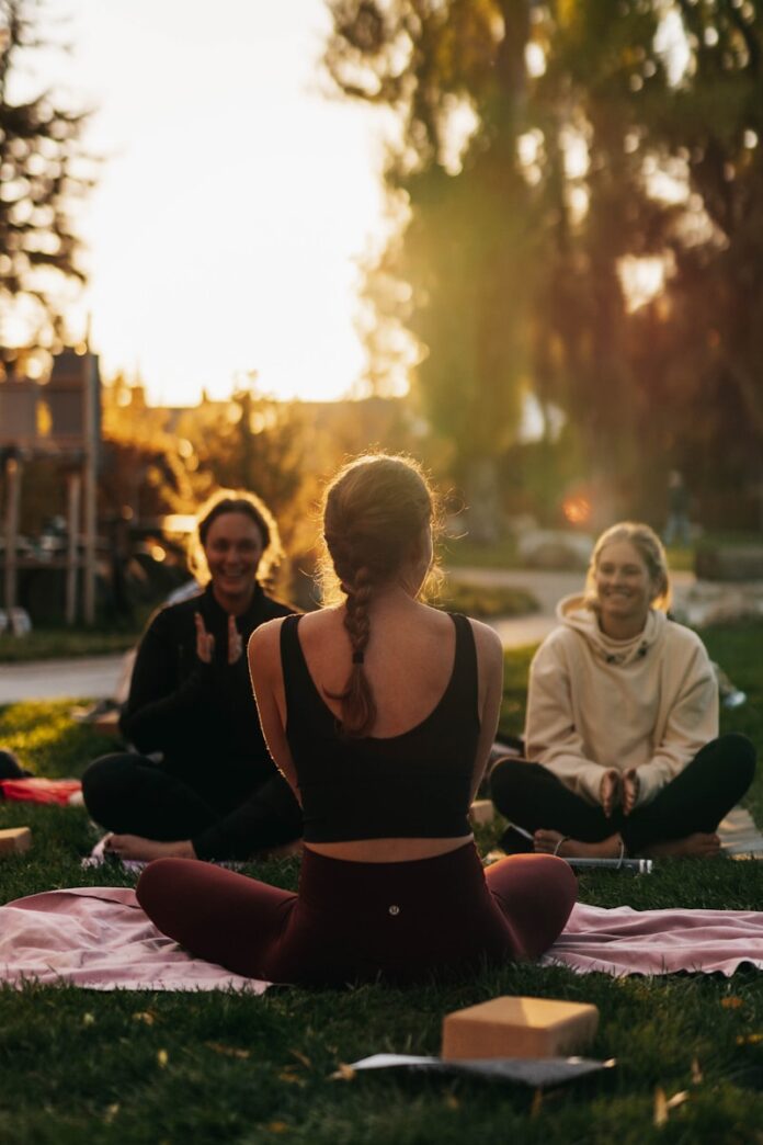 Photo by Marea Wellness a group of people sitting on top of a lush green field