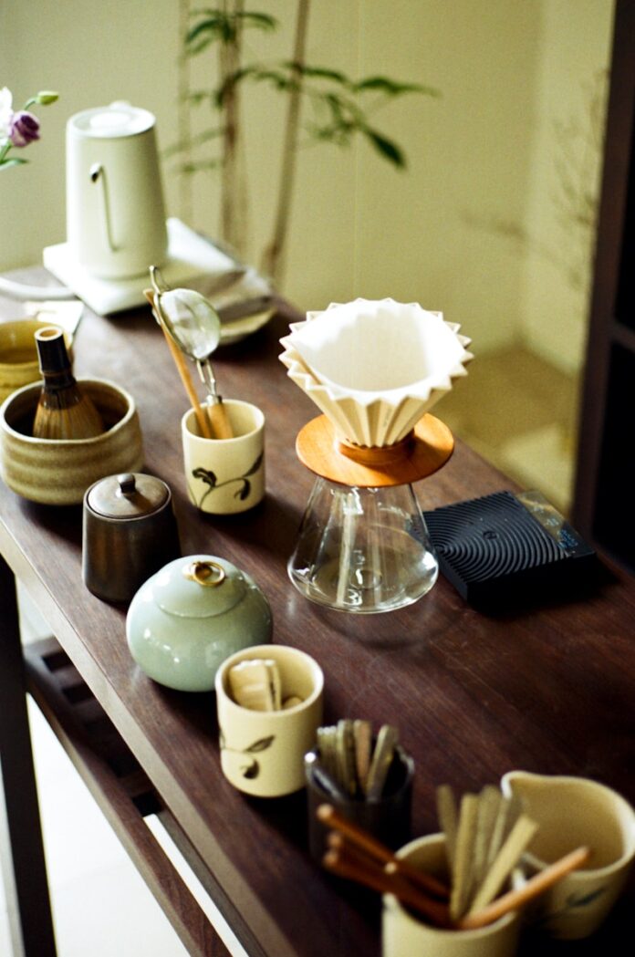 Photo by Khanh Do Various tea ceremony utensils arranged on a wooden table.